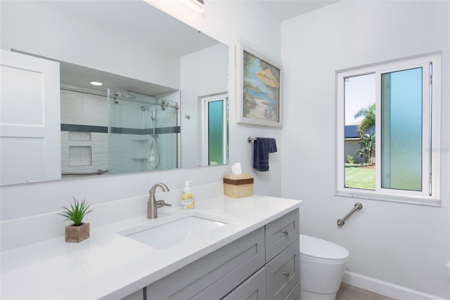 full bathroom with baseboards, vanity, a shower stall, and toilet