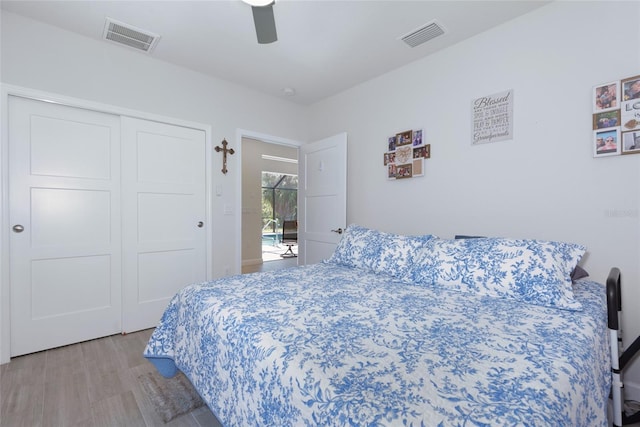 bedroom featuring visible vents, a closet, wood finished floors, and a ceiling fan