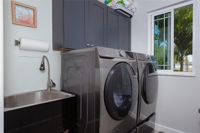 washroom featuring a sink, cabinet space, baseboards, and washer and clothes dryer