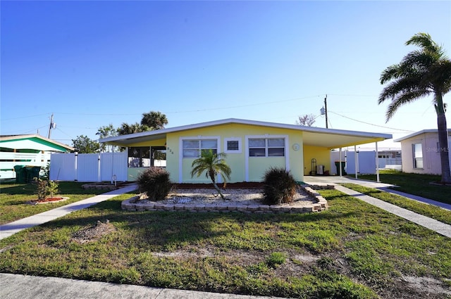 view of front of property with a carport, fence, a front yard, and driveway