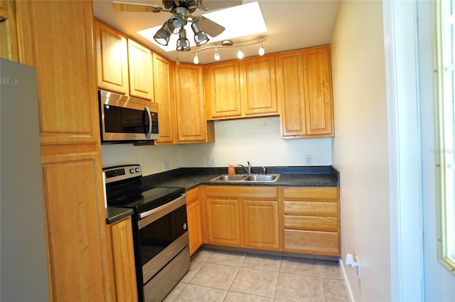 kitchen featuring dark countertops, ceiling fan, light tile patterned flooring, stainless steel appliances, and a sink