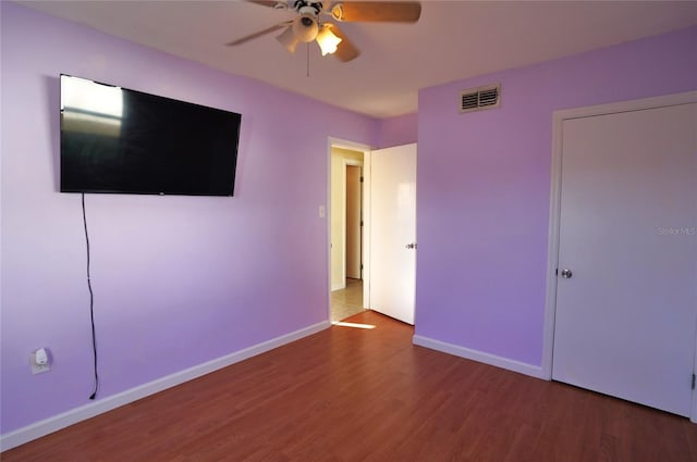 unfurnished bedroom featuring visible vents, a ceiling fan, baseboards, and wood finished floors