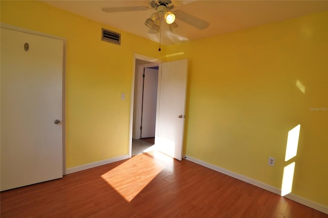 spare room with ceiling fan, wood finished floors, visible vents, and baseboards