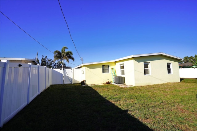 rear view of property featuring a gate, central AC unit, a yard, and a fenced backyard