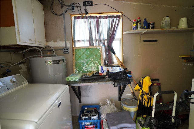 clothes washing area with washer / clothes dryer, cabinet space, and water heater