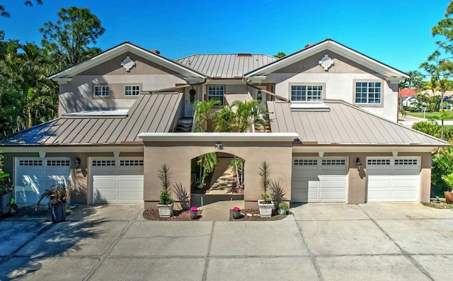 view of front of home featuring stucco siding, an attached garage, metal roof, and a standing seam roof