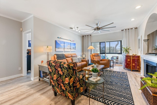 living area featuring light wood-type flooring, ornamental molding, a ceiling fan, recessed lighting, and baseboards