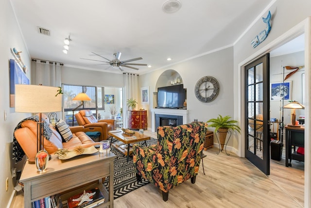 living room with a glass covered fireplace, light wood-style flooring, a healthy amount of sunlight, and visible vents