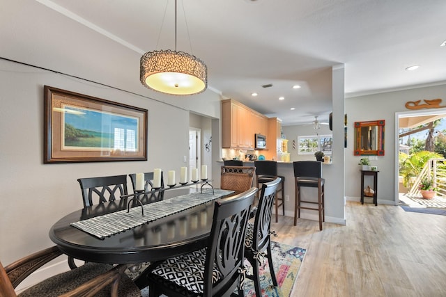 dining space with baseboards, a healthy amount of sunlight, ornamental molding, and light wood finished floors