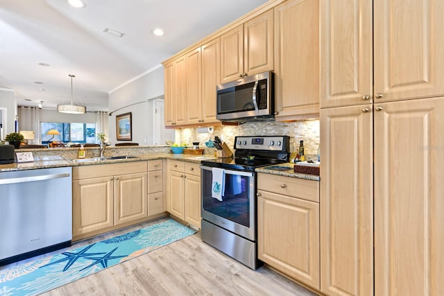 kitchen featuring light brown cabinetry, light stone countertops, appliances with stainless steel finishes, and a sink