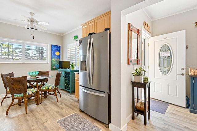 kitchen with stainless steel fridge, light wood-style floors, ornamental molding, and light brown cabinetry