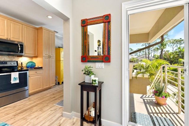 kitchen featuring light wood-type flooring, stainless steel appliances, backsplash, and light brown cabinetry