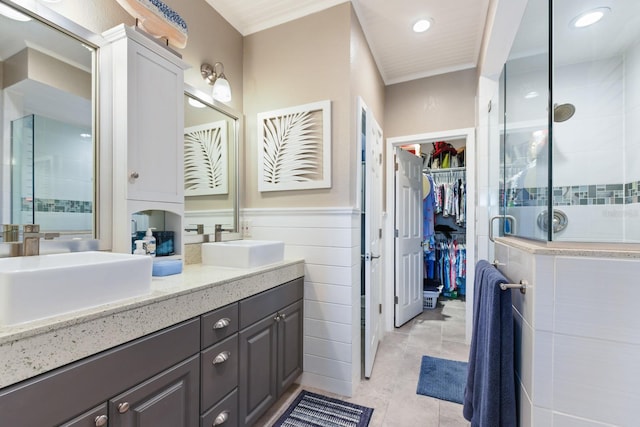 bathroom with wainscoting, a shower stall, a spacious closet, and a sink