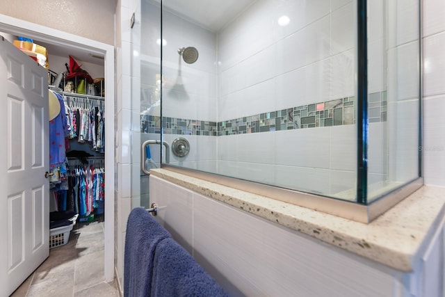 full bathroom with a spacious closet and a tile shower