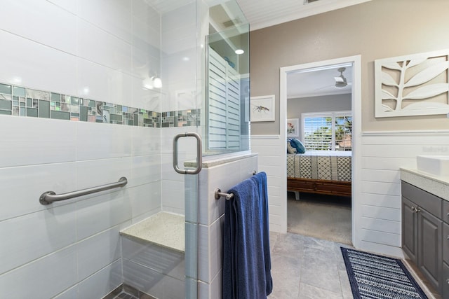 full bath featuring vanity, ornamental molding, a wainscoted wall, and a stall shower