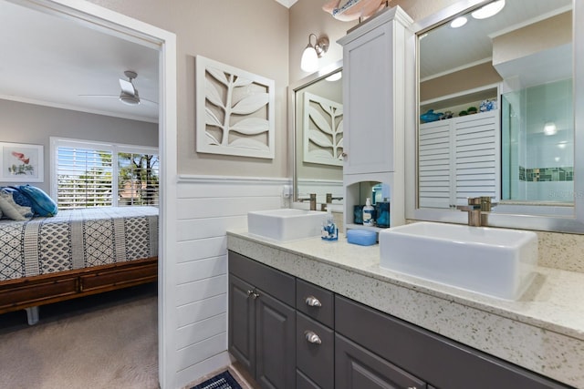 bathroom with crown molding, connected bathroom, wainscoting, and a sink