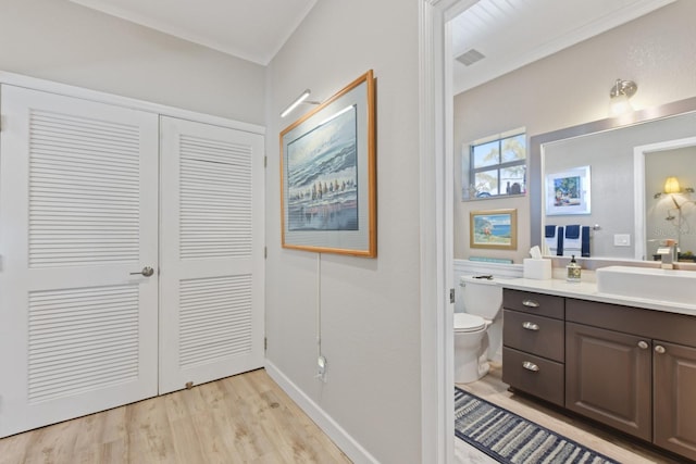 bathroom with vanity, wood finished floors, visible vents, baseboards, and toilet