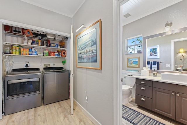 washroom with visible vents, independent washer and dryer, light wood-style flooring, a sink, and laundry area