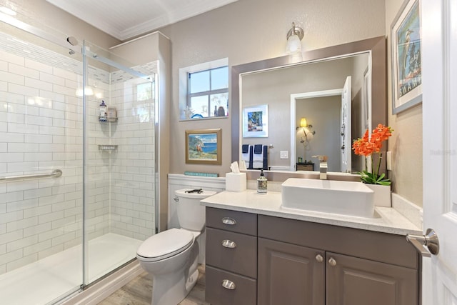 bathroom with vanity, toilet, a shower stall, and crown molding