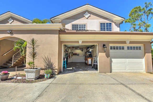 exterior space with stucco siding, a garage, and driveway