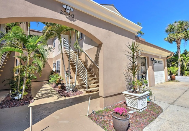 entrance to property with concrete driveway, an attached garage, and stucco siding