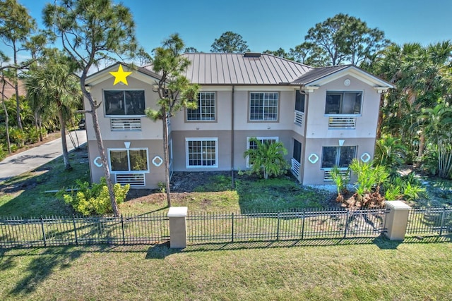 view of front of home featuring a standing seam roof, a front lawn, metal roof, and stucco siding