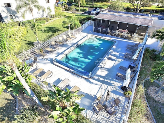 pool featuring a patio, fence, and a sunroom