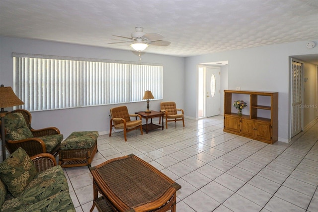 living area featuring light tile patterned floors, a ceiling fan, and baseboards