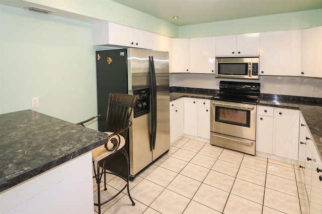 kitchen featuring stainless steel appliances, visible vents, light tile patterned flooring, and white cabinets