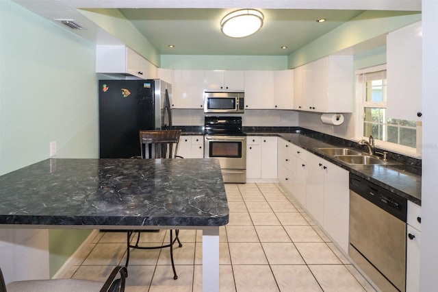 kitchen featuring visible vents, light tile patterned floors, white cabinets, stainless steel appliances, and a sink