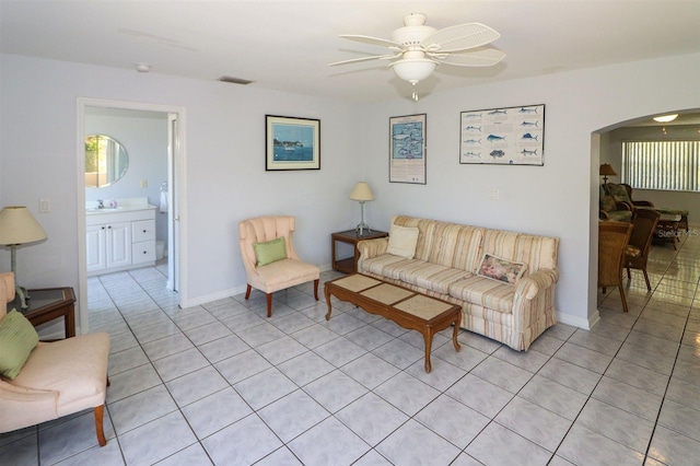 living room with visible vents, baseboards, light tile patterned flooring, arched walkways, and a ceiling fan