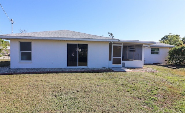 back of property featuring a yard, a sunroom, and stucco siding