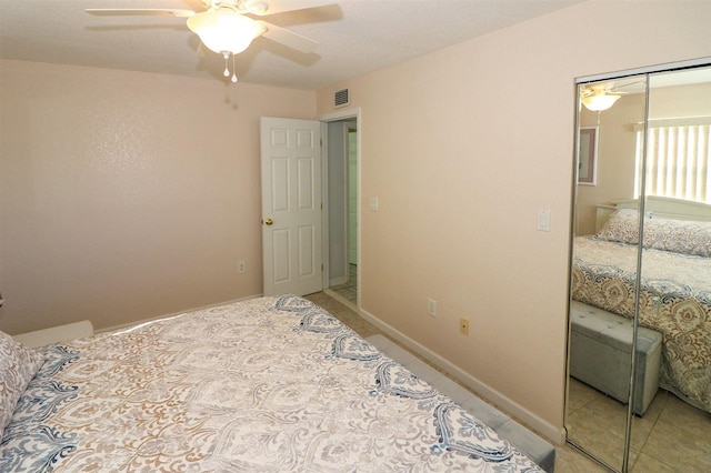 bedroom with visible vents, a ceiling fan, a closet, light tile patterned flooring, and baseboards