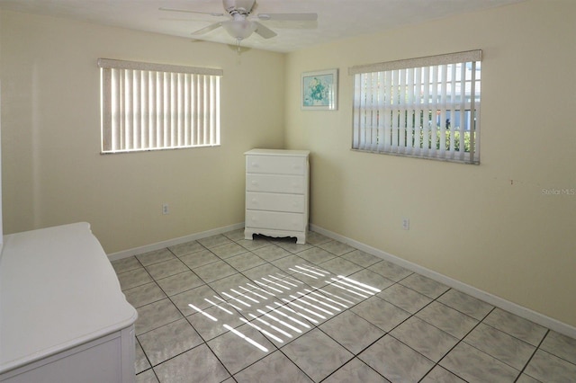 empty room featuring light tile patterned flooring, a healthy amount of sunlight, baseboards, and ceiling fan