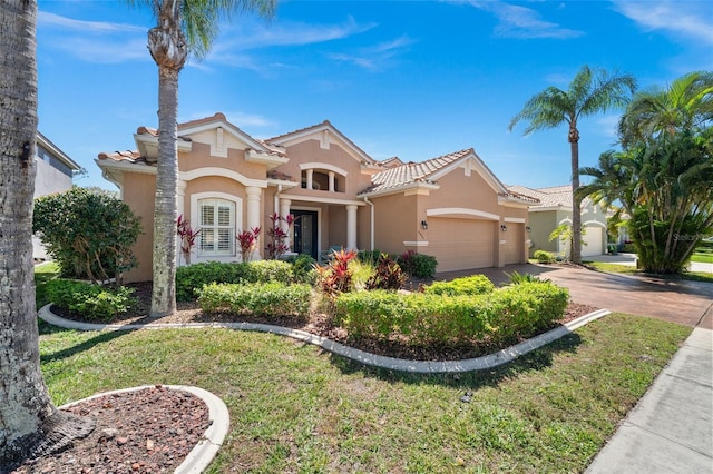 mediterranean / spanish-style home featuring a tile roof, an attached garage, driveway, and stucco siding