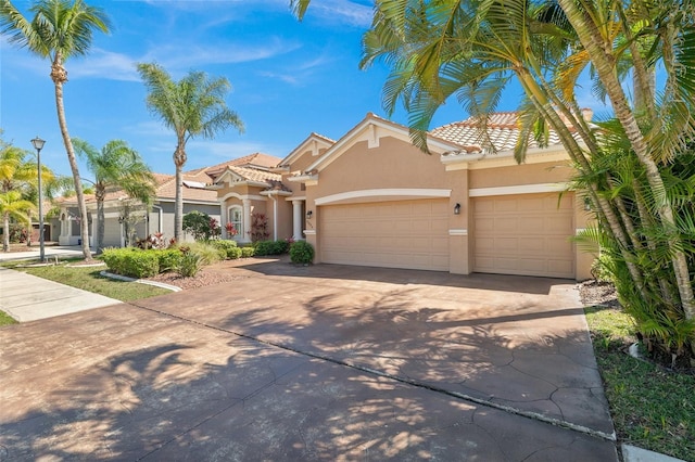 mediterranean / spanish-style home with stucco siding, a garage, driveway, and a tile roof