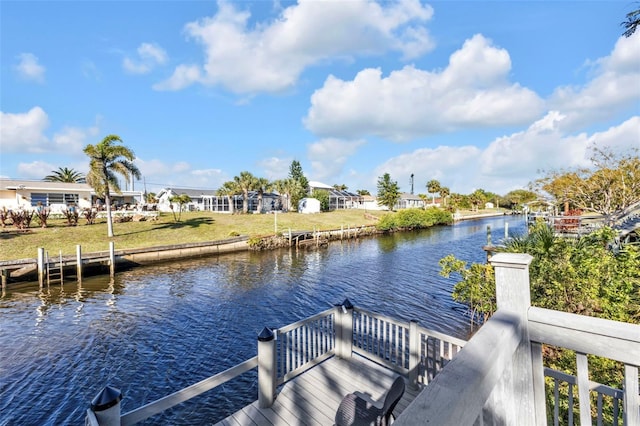 view of dock with a lawn and a water view