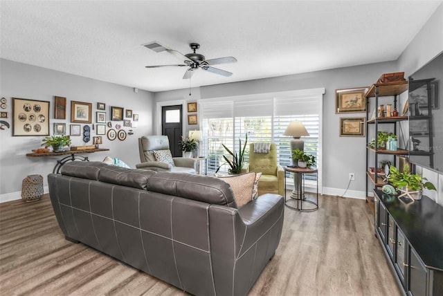 living room featuring visible vents, baseboards, ceiling fan, and wood finished floors