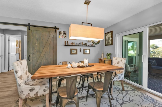 dining space featuring a barn door and light wood-style floors