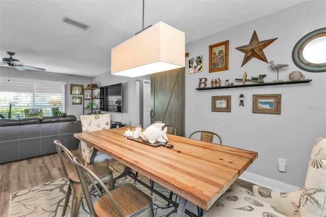 dining space with visible vents, a ceiling fan, a textured ceiling, wood finished floors, and baseboards