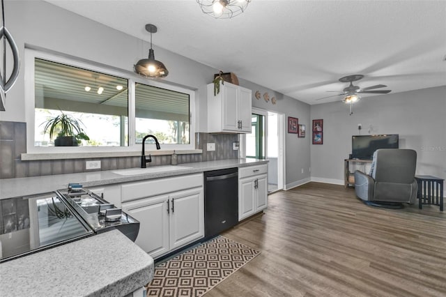 kitchen with light countertops, black dishwasher, dark wood-style floors, white cabinetry, and a sink