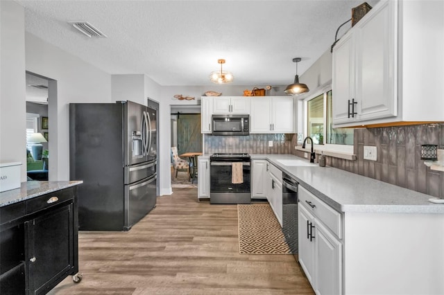 kitchen with visible vents, a sink, appliances with stainless steel finishes, white cabinets, and light wood finished floors