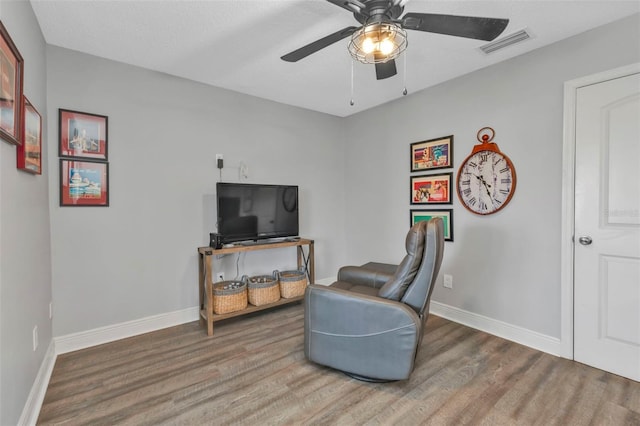 sitting room with baseboards, wood finished floors, visible vents, and ceiling fan