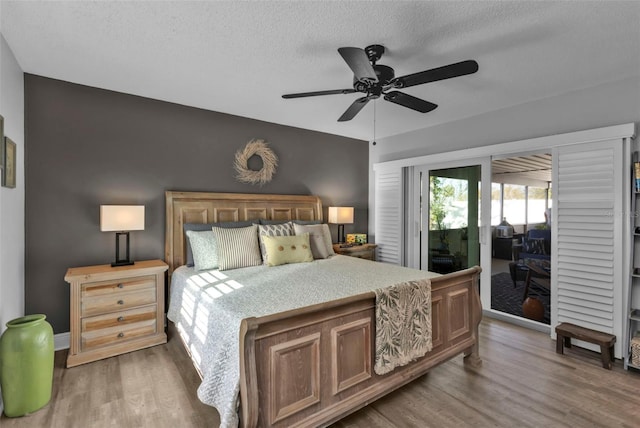 bedroom with baseboards, wood finished floors, a textured ceiling, a ceiling fan, and access to outside