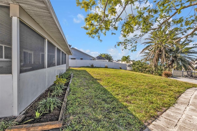 view of yard with a garden, a fenced backyard, and a sunroom