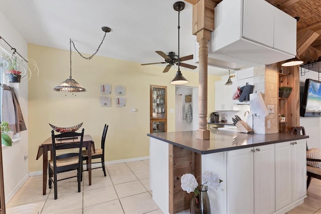 kitchen featuring dark countertops, white cabinets, light tile patterned floors, and decorative light fixtures