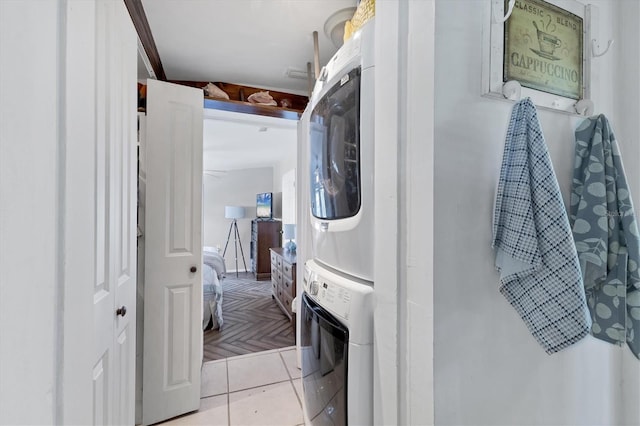 laundry area featuring light tile patterned floors, stacked washer / dryer, and laundry area