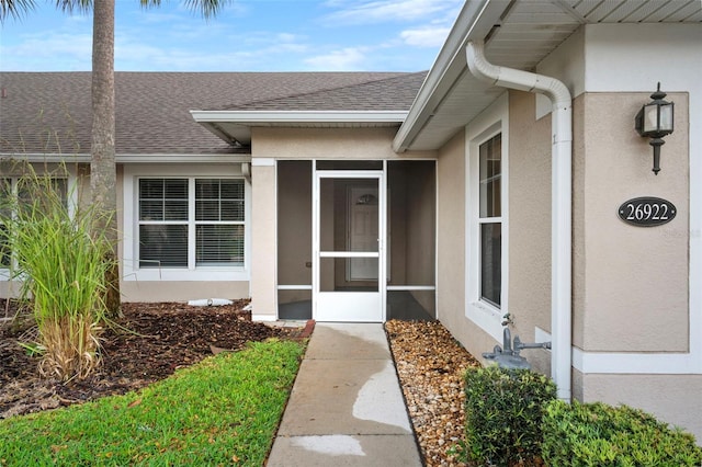 property entrance with stucco siding and roof with shingles