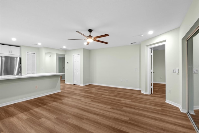 unfurnished living room with recessed lighting, baseboards, and wood finished floors