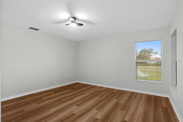 spare room with visible vents, baseboards, a textured ceiling, and wood finished floors